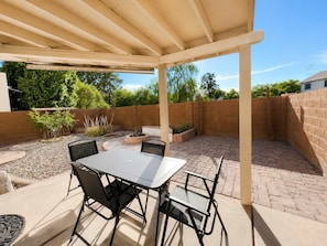 An outdoor patio with a table and chairs, surrounded by a brick wall and greenery. - Wow! Single-story 3BR Chandler home (Chandler)