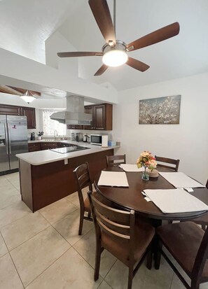 A modern kitchen with a central island, dark wooden cabinets, stainless steel appliances, and a ceiling fan. - Wow! Single-story 3BR Chandler home (Chandler)