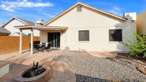 A residential building with a covered patio area, a fire pit, and a gravel driveway.