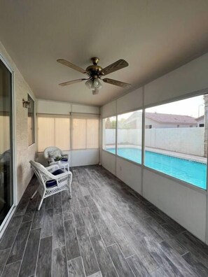 A balcony with a pool, grey tiled flooring, a ceiling fan, and a white wicker chair. - Pet-Friendly 3BR | Private Pool | Game Room (Chandler)