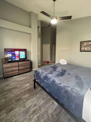 A bedroom with a bed, a dresser, a TV, and a ceiling fan. - Pet-Friendly 3BR | Private Pool | Game Room (Chandler)