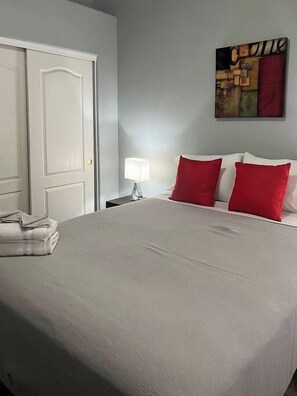 A hotel room with a bed, a nightstand, a lamp, and a painting on the wall.