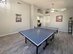 A spacious room with a ping pong table, a small arcade machine, and a framed picture on the wall. - Pet-Friendly 3BR | Private Pool | Game Room (Chandler)