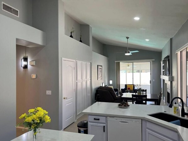 A modern kitchen with white cabinetry, a central island, and a dining area with a table and chairs.