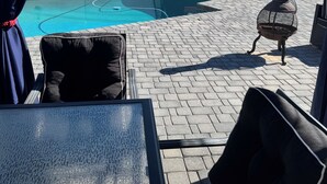 Un espace piscine avec un patio, des sièges d’extérieur et un drapeau accroché au mur.