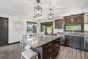 A modern kitchen with a granite countertop, dark cabinetry, and pendant lighting.