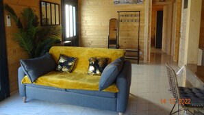 A wooden interior with a sofa, a mirror, and a plant.