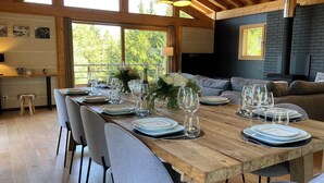 Un coin repas avec une table en bois dressée pour six personnes, entourée de chaises grises.