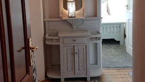 A hallway with a wooden door, a white vanity with a mirror, and a patterned rug.