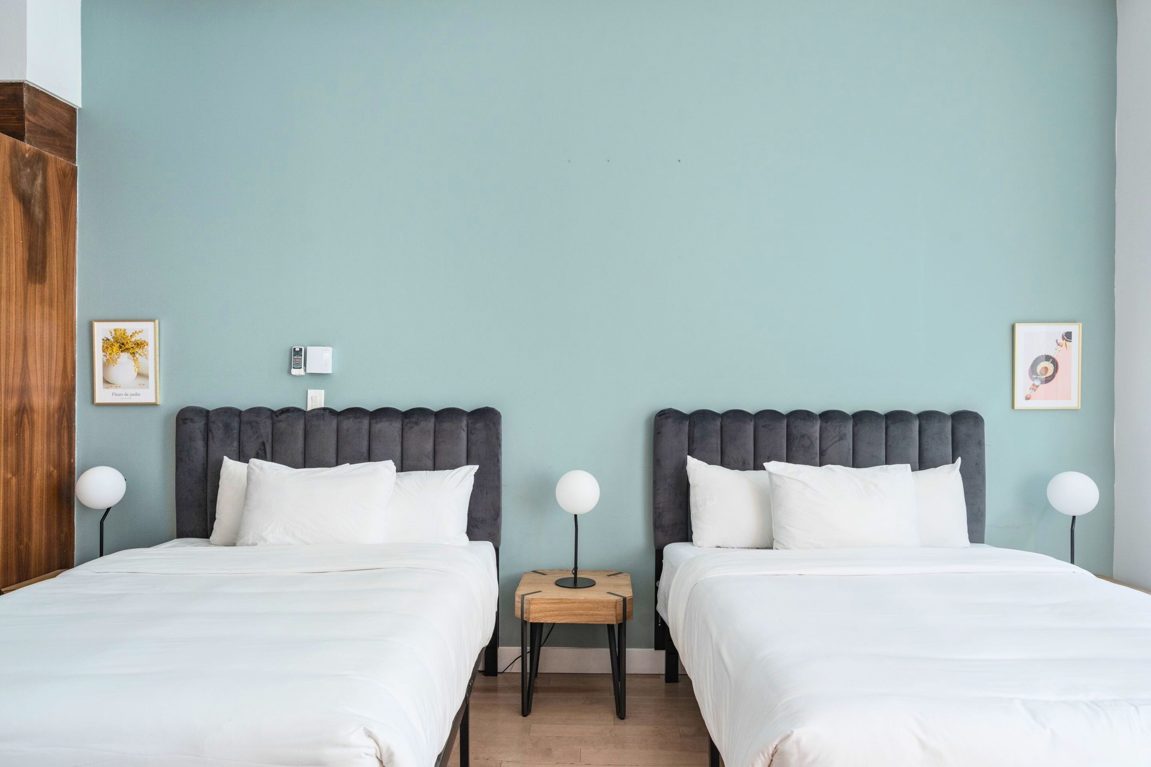 Une chambre d’hôtel avec deux lits, une petite table de chevet en bois et un téléphone fixé au mur.