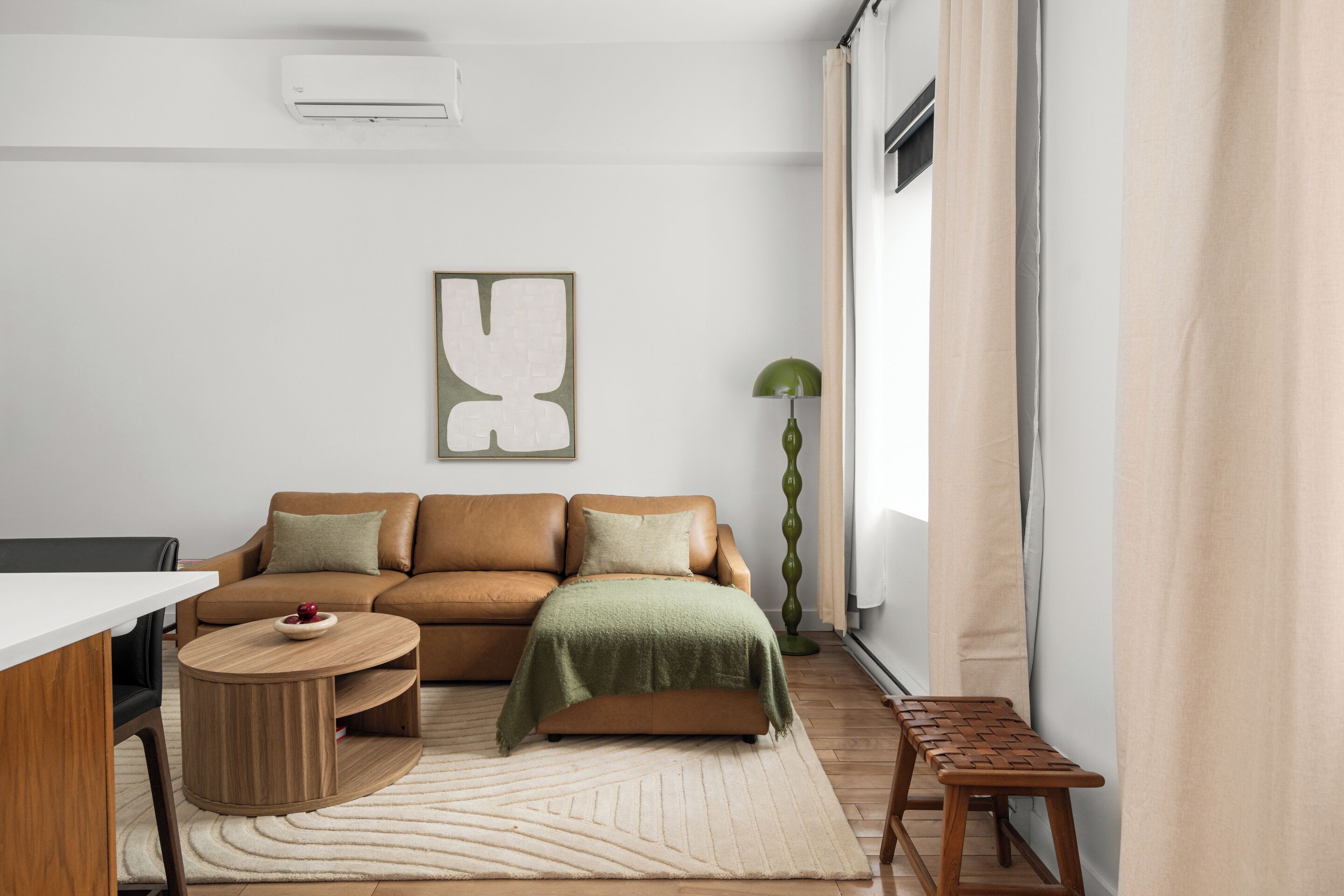 Una sala de estar moderna con un sofá, una mesa de centro, un banco y una lámpara de pie.