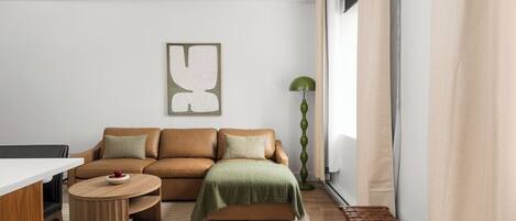 Una sala de estar moderna con un sofá, una mesa de centro, un banco y una lámpara de pie.