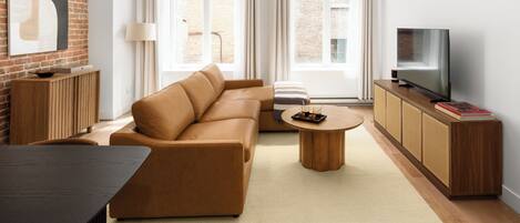 Un salon moderne avec un canapé, une table basse, un téléviseur et un mur en briques.