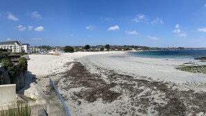 Une plage avec un rivage sablonneux, un ciel bleu dégagé et des bâtiments en arrière-plan.