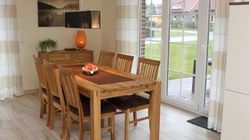 A dining area with a wooden table and chairs, a vase, and a painting on the wall.