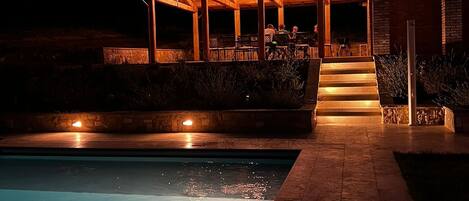 A pool area with a covered patio and steps leading to a building.