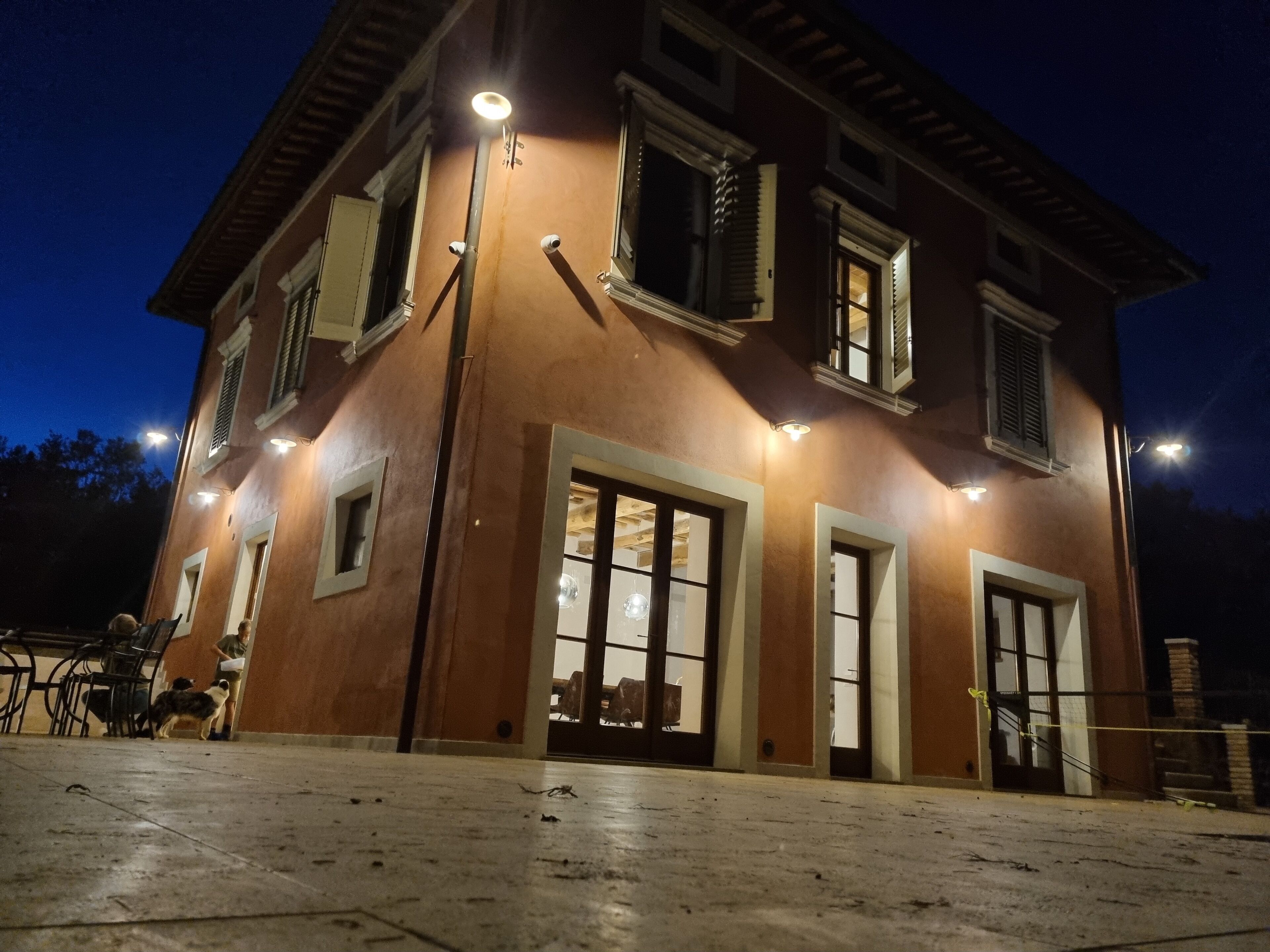 A two-story building with multiple windows and doors, illuminated by exterior lights.