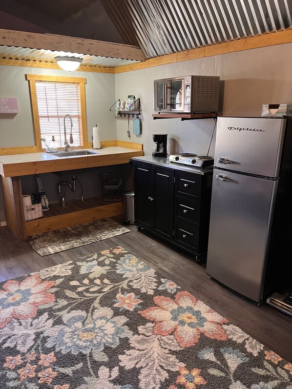A compact kitchen with a sink, stove, refrigerator, and a microwave. - Glamping Getaway - Tiny home on 143 acres of beauty! (Eureka Springs)
