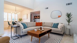 Uma sala de estar moderna com sofá, mesa de centro e um espaço de jantar com cadeiras.