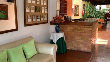 Un vestíbulo de hotel con un sofá de cuero, un mostrador de recepción y un suelo de baldosas.