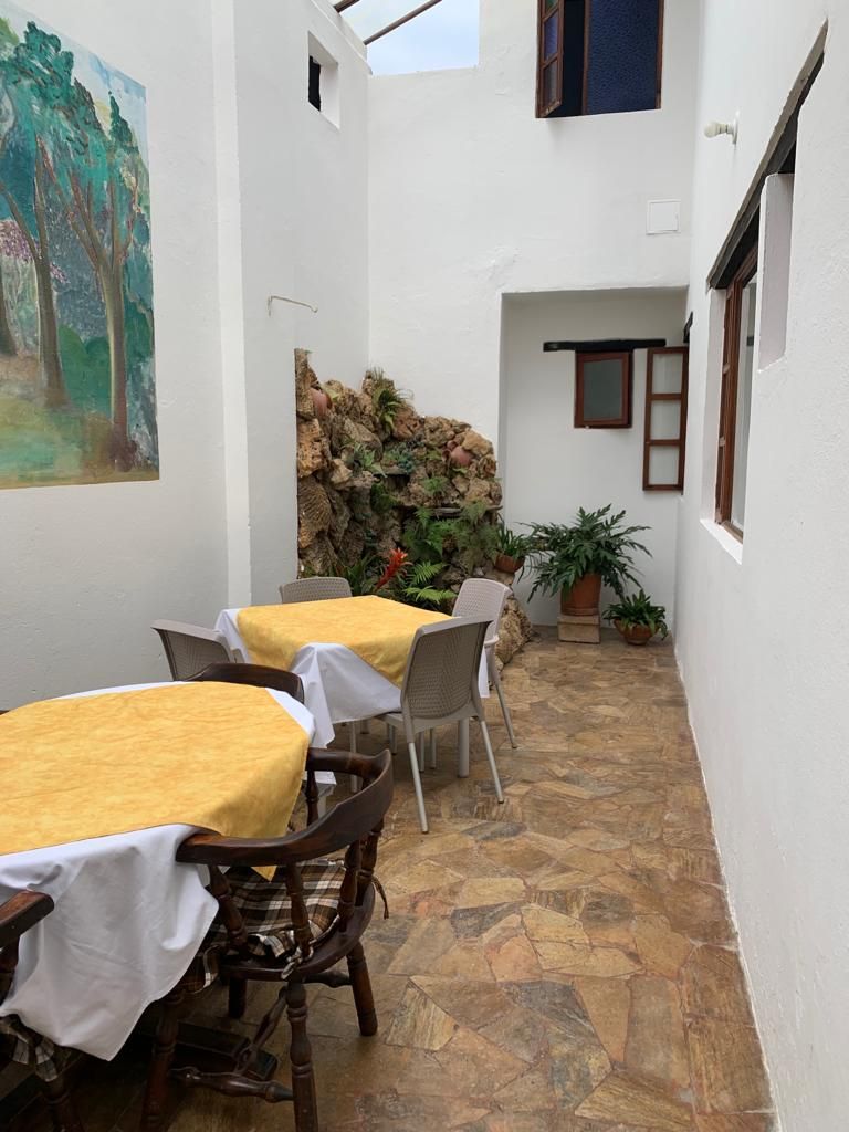 Un pequeño espacio al aire libre con mesas y sillas, una pared de piedra y un cuadro en la pared.