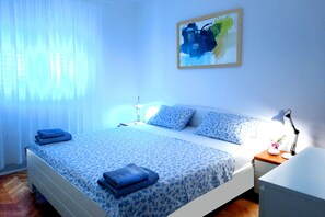 A bedroom with a bed, a nightstand, a lamp, and a painting on the wall.