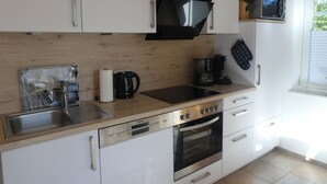 A modern kitchen with white cabinets, a black microwave, a coffee maker, and a Siemens dishwasher.