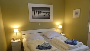 A neatly made bed with white linens, two bedside tables with lamps, and a framed picture on the wall.