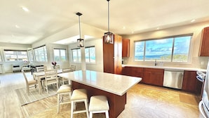 Una cocina amplia con una isla grande, armarios de madera y vista al océano.