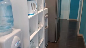 Ett kompakt kök med kylskåp, mikrovågsugn, vattenautomat och en vattenkylare.
