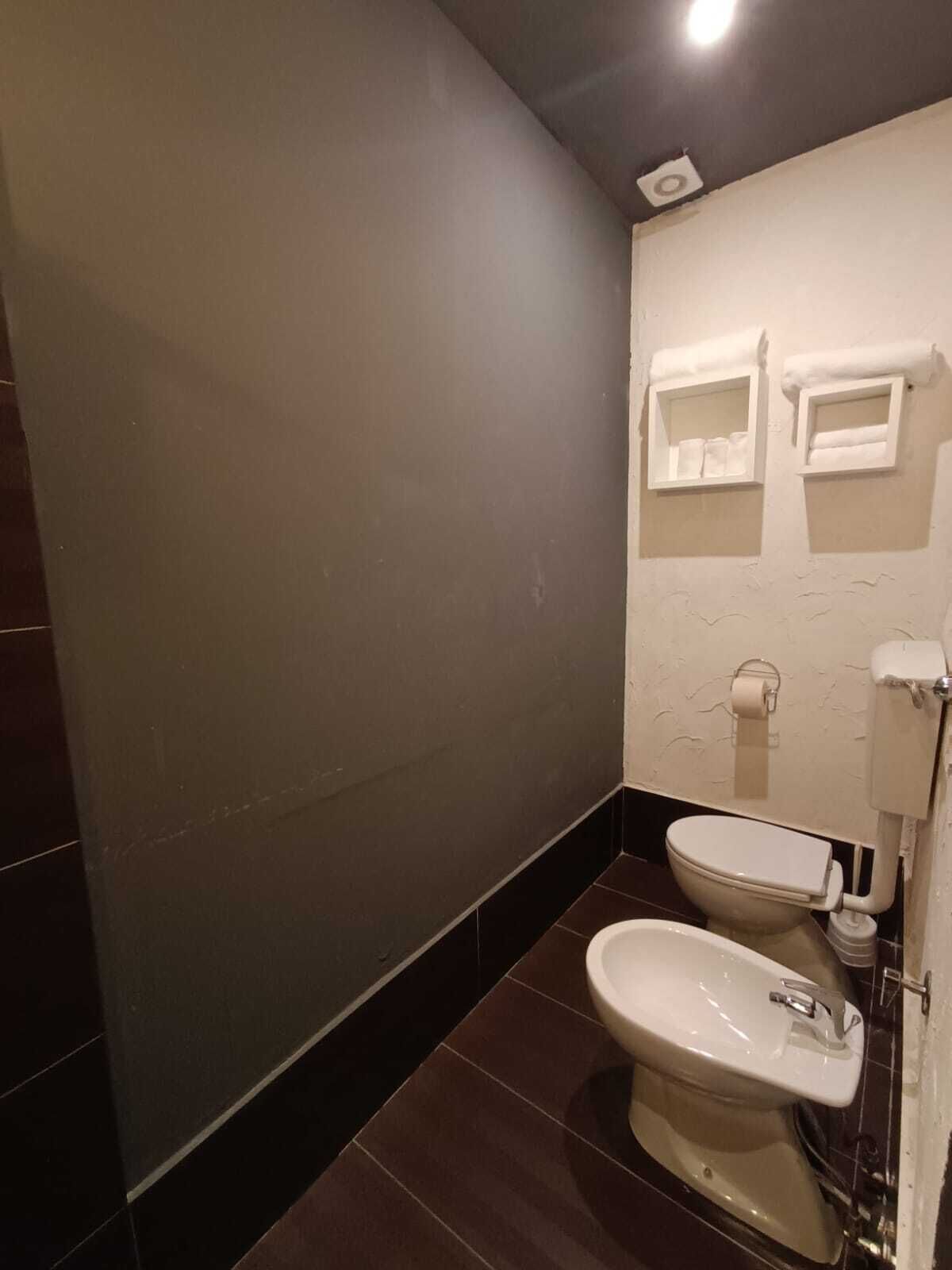 A modern bathroom with two toilets, a sink, and a toilet paper holder.