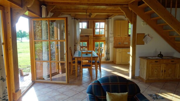 A wooden interior with a dining area, kitchen, and a staircase. - Vacation home with large meadow on nature reserve lake (Petershagen)
