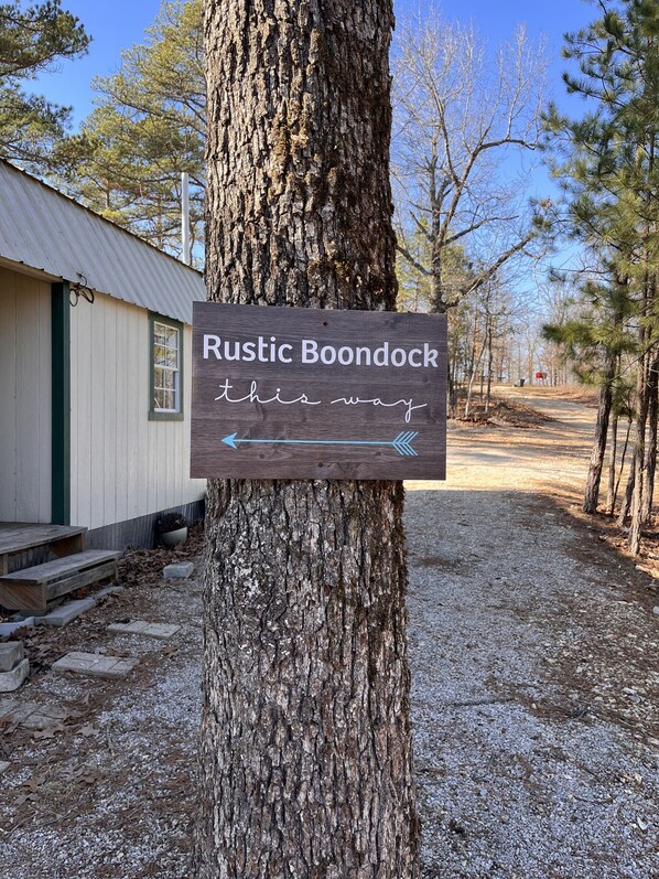 A rustic boondock sign with a directional arrow pointing to the right, indicating a path.