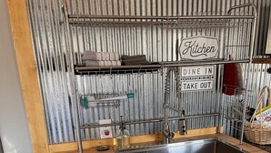 A compact kitchen with a stainless steel sink, wooden countertop, and a metal rack with kitchen utensils. - Rustic Boondock - Peaceful tiny home on 143 acres! (Eureka Springs)