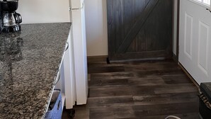 A kitchen with a granite countertop, a white refrigerator, a coffee maker, and a wooden door. - Rustic Boondock - Peaceful tiny home on 143 acres! (Eureka Springs)