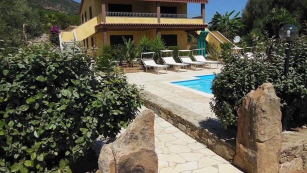 Un bâtiment à deux étages doté d’une piscine et de chaises longues.