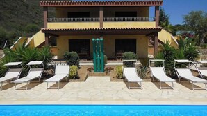 Un hôtel doté d’une piscine, de chaises longues et offrant une vue sur un paysage montagneux.