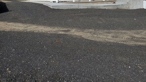 Une maison à deux étages avec un porche à l’avant, une cheminée et une allée gravillonnée.