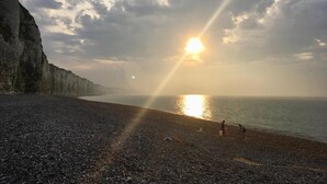 A beach with a rocky shoreline and cliffs in the background. - Family chateau in the middle of its large wooded park. (Hugleville-en-Caux)