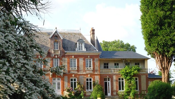 A large, historic building with a symmetrical facade, multiple windows, and a prominent chimney. - Family chateau in the middle of its large wooded park. (Hugleville-en-Caux)