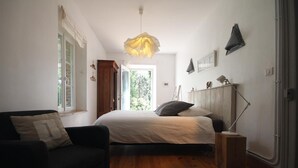A bedroom with a bed, a desk, a chair, a sofa, and a large window. - Family chateau in the middle of its large wooded park. (Hugleville-en-Caux)