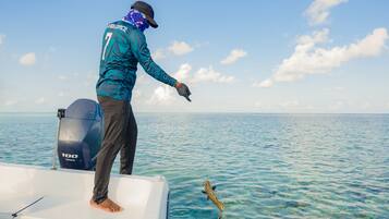 Una persona en un bote con motor fueraborda Yamaha, pescando en aguas azul turquesa.
