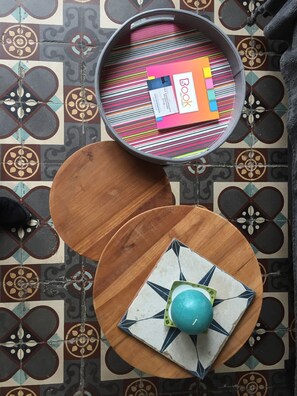 A room with a patterned floor, a round table with a colorful striped tablecloth, and a decorative plate with a blue center. - 50 meters from the beach, lovely accommodations for 6 people (Les Sables-d'Olonne)