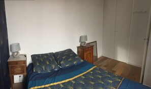 A bedroom with a bed, two bedside tables, a nightstand, a mirror, and a wardrobe.