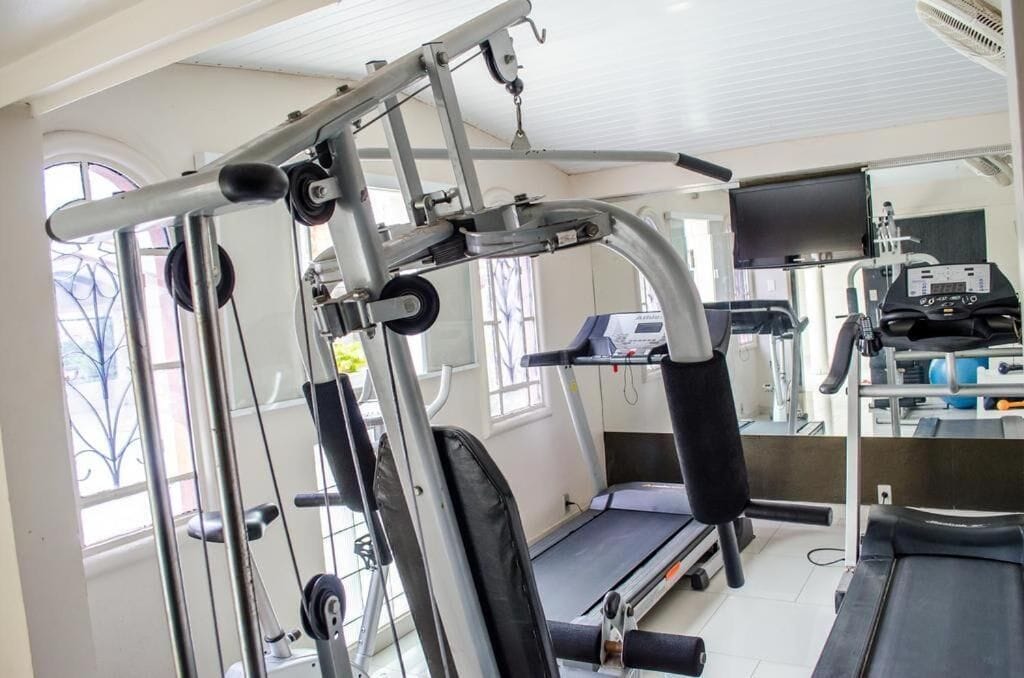 Un gimnasio con equipo de ejercicio, cinta de correr y un espejo grande.