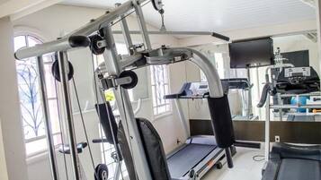 Un gimnasio con equipo de ejercicio, cinta de correr y un espejo grande.