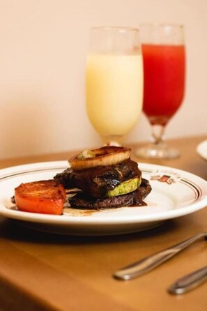Une assiette de nourriture accompagnée d'un verre de boisson blanche et d'un verre de boisson rouge.