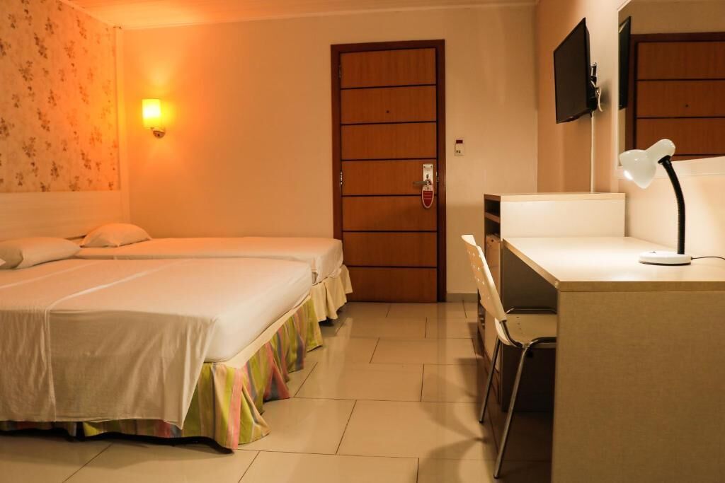 Une chambre d’hôtel avec deux lits, un bureau, une chaise, une télévision et une porte.