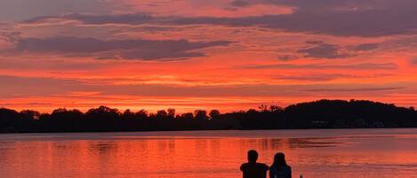 Un coucher de soleil sur un lac paisible, avec un quai et un bateau.