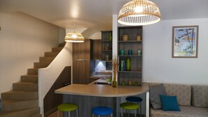 A modern kitchen with a central island, bar stools, and a staircase. - Cozy villa 🌞, air-conditioned, 5' walk to San Ciprianu beach 🌊 (Lecci)